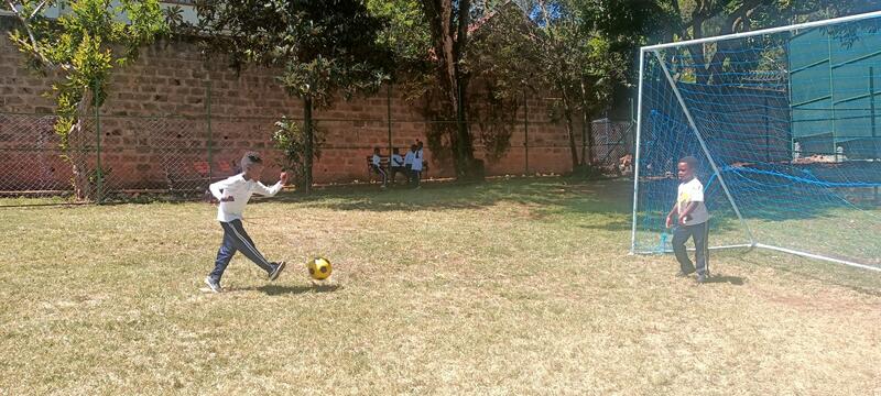 Students playing football on the grass sports field