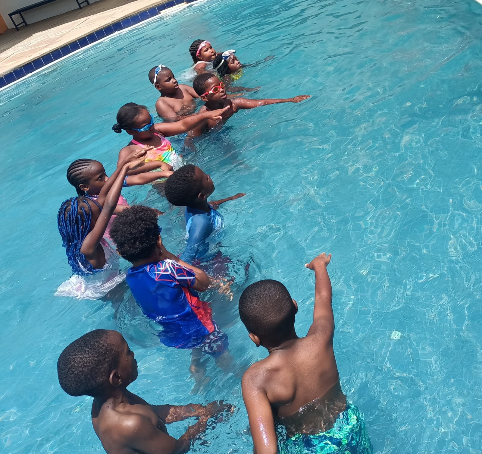 Students practising strokes in a line during a swimming lesson