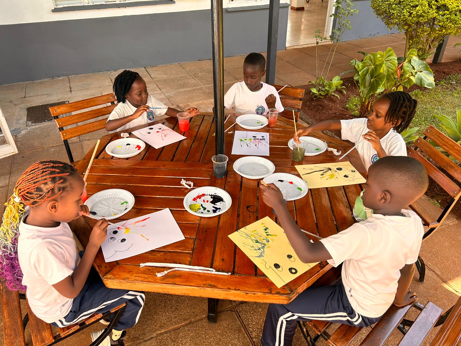 Students straw-painting at the outdoor art table